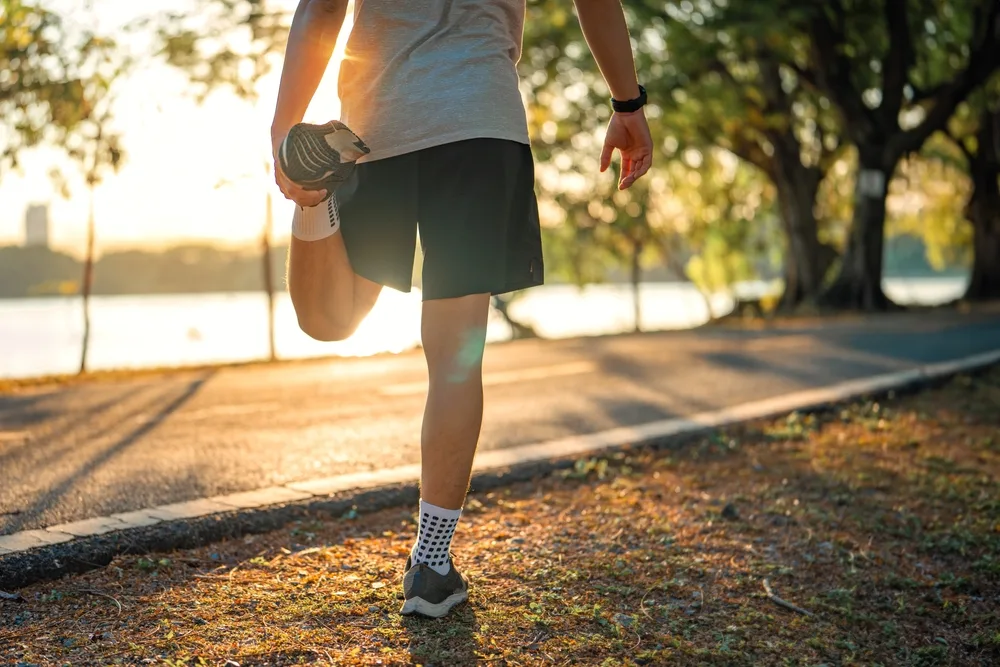 Person stretching before run - Tobin C Gallawa DPM FACFAS A man stretching before a run outdoors while the sun is rising - Tobin C Gallawa DPM FACFAS