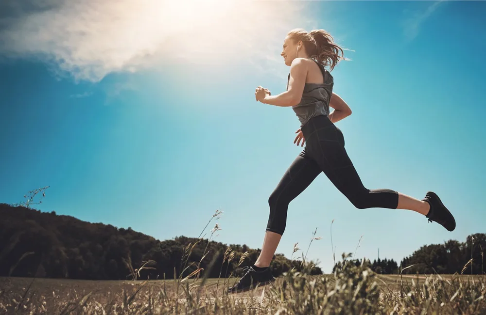 A woman in athletic clothing runs outdoors across a grassy field under a bright blue sky - Tobin C Gallawa DPM FACFAS A woman in athletic clothing runs outdoors across a grassy field under a bright blue sky - Tobin C Gallawa DPM FACFAS